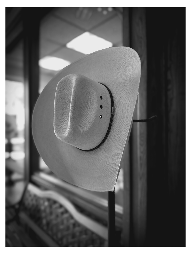 A cowboy hat hanging on a post. 